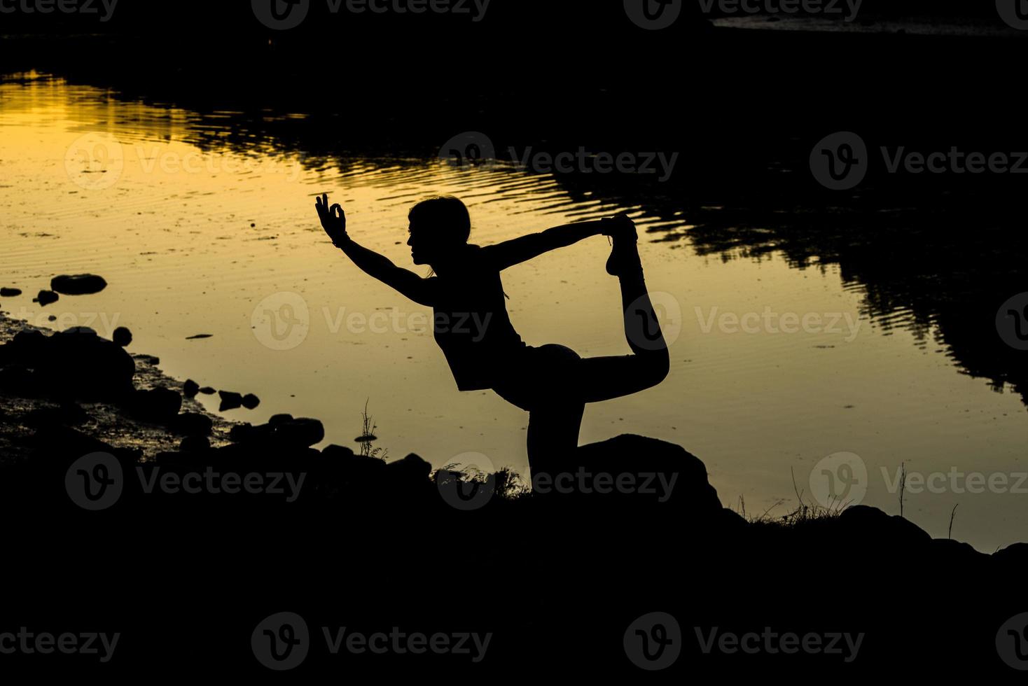 silhuetas de uma mulher fazendo ioga ao pôr do sol foto