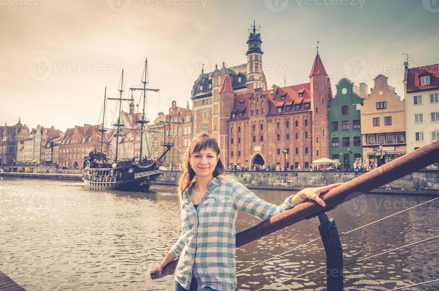 jovem viajante com camisa olhando para a câmera e sorriso, navio de madeira medieval e aterro do rio motlawa foto