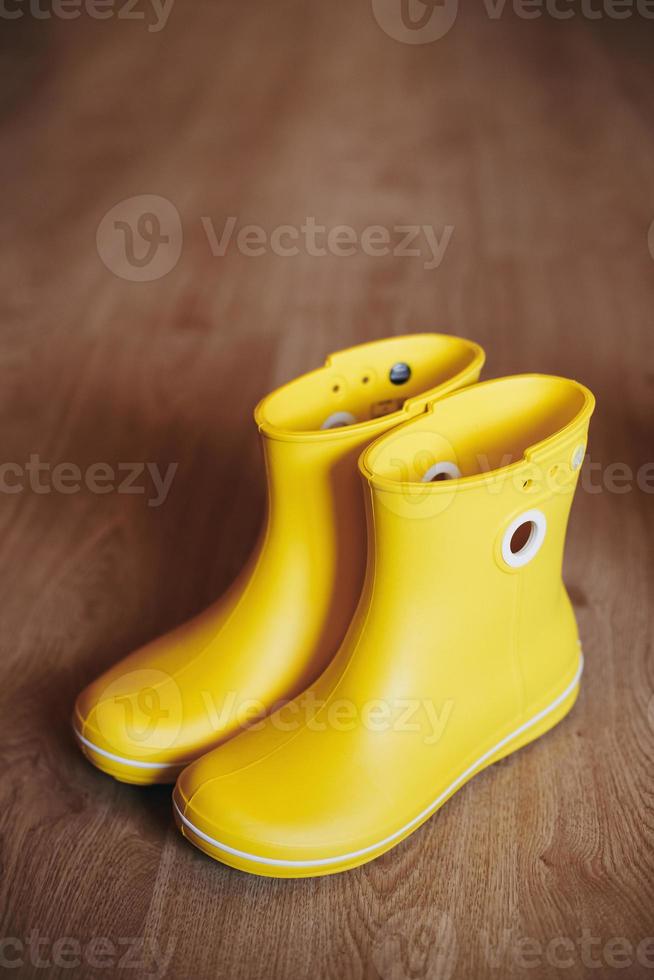 botas de borracha amarelas isoladas em fundo de madeira foto
