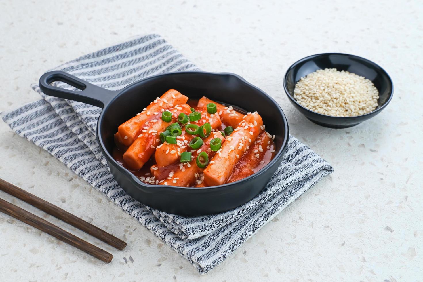 tteokbokki ou topokki, palito de bolo de arroz frito, comida de rua coreana popular com molho picante de gochujang e sementes de gergelim. foto