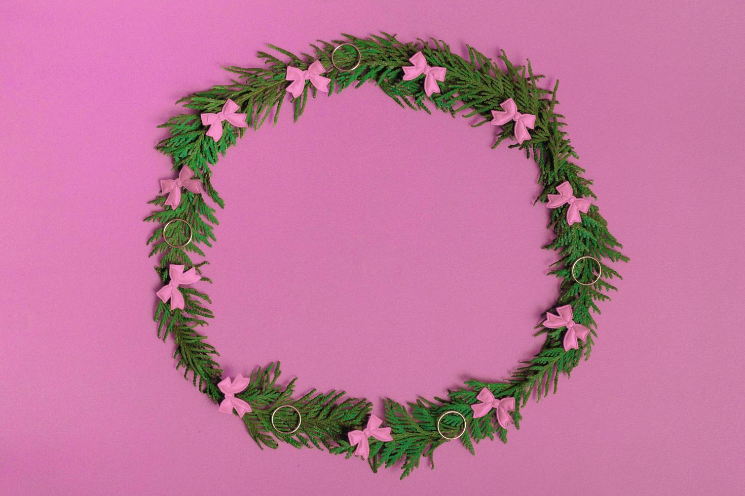 guirlanda de Natal de galhos de pinheiro e decorações em um fundo rosa. disposição plana, vista superior, espaço de cópia. composição festiva foto