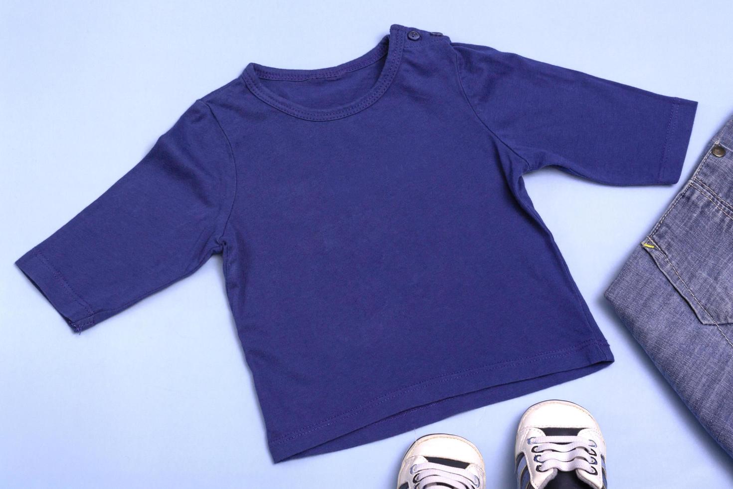 maquete para design e colocação de logotipos, publicidade. raglan infantil azul, polo, vista superior da blusa, maquete sobre um fundo azul. foto