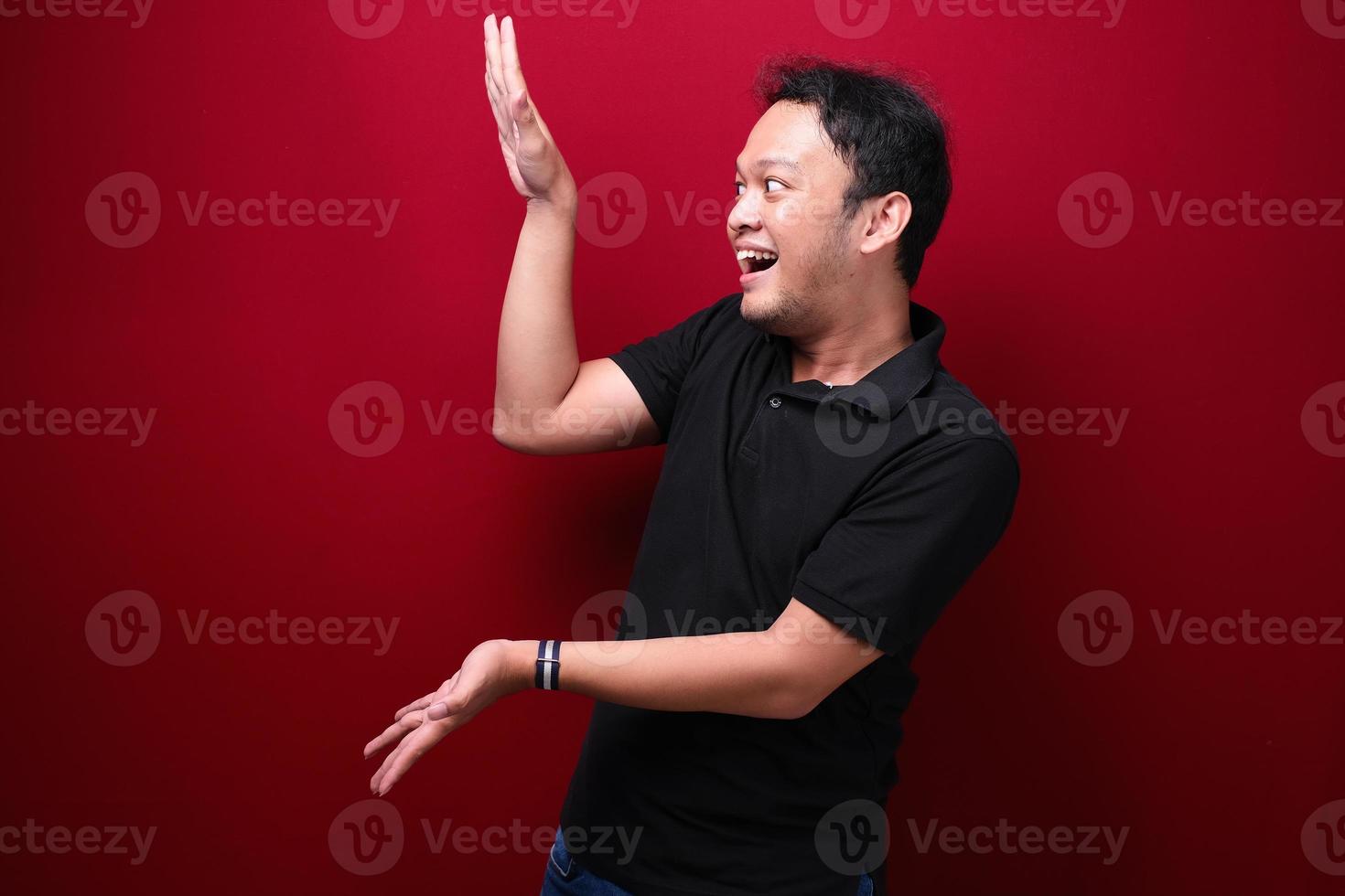 sorriso e feliz jovem asiático está com o ponto de mão no espaço vazio foto