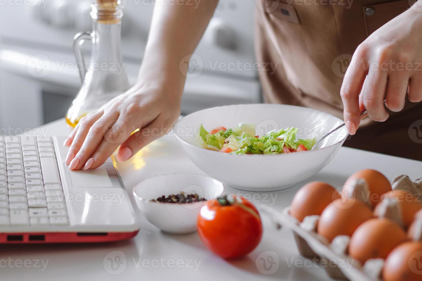 mulher preparando uma salada de dieta usando o livro de receitas digital. foto