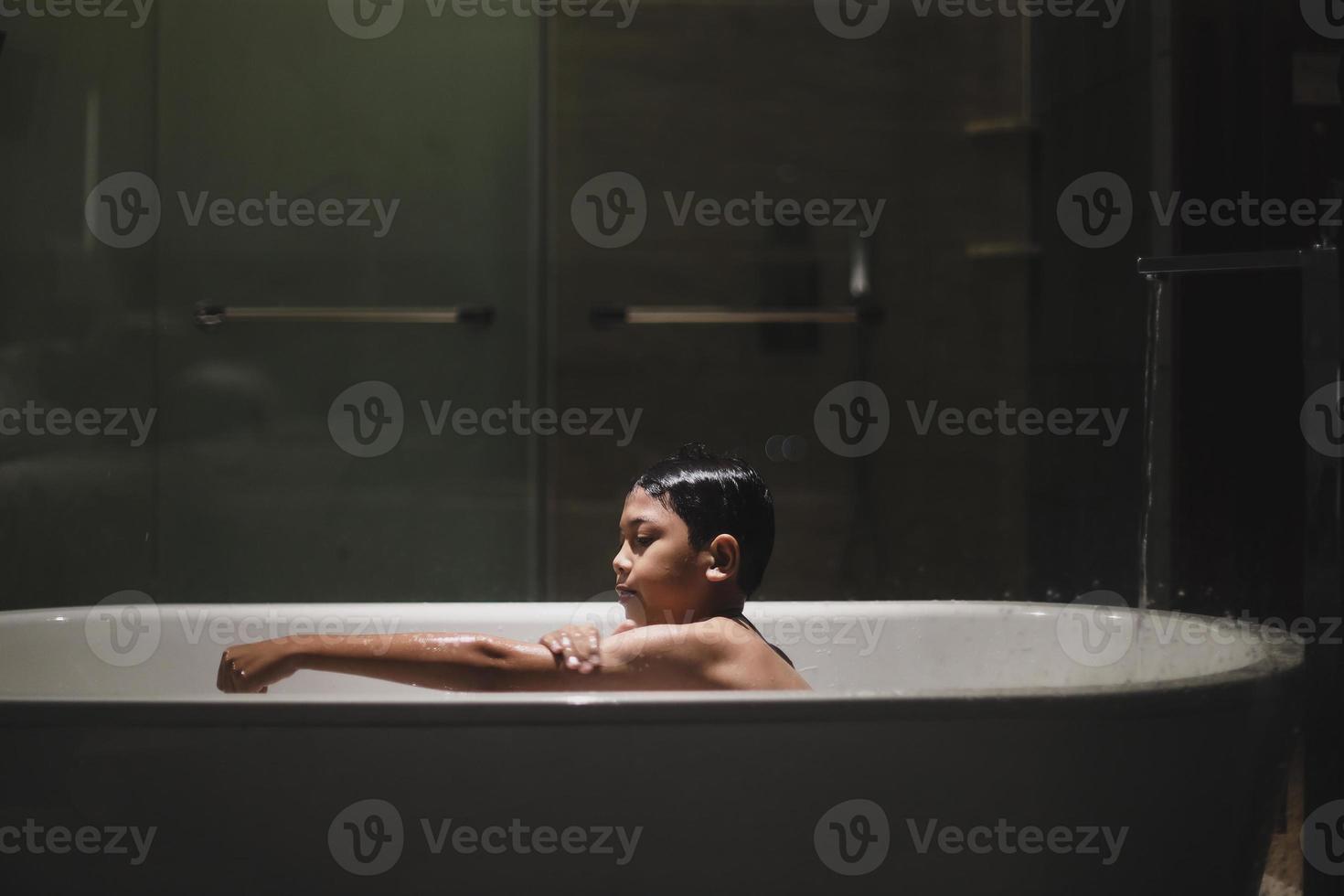 menino asiático tomando banho na banheira foto