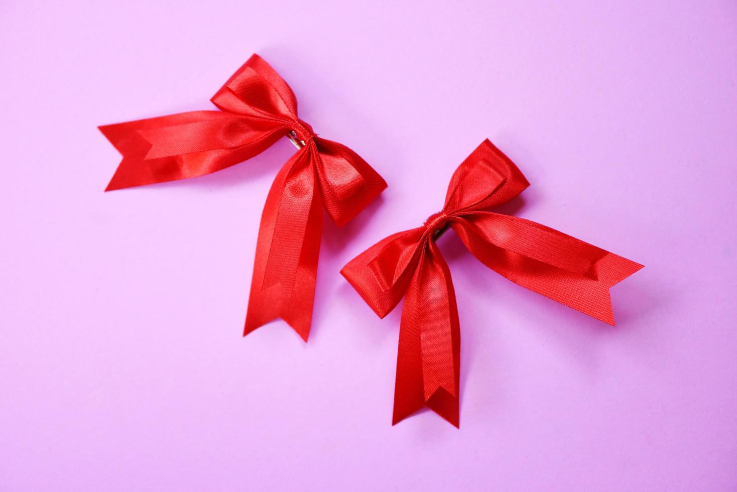 laço de fita vermelha em fundo rosa - dois arcos de presente, grampo de cabelo, feriado perfeito feito à mão foto