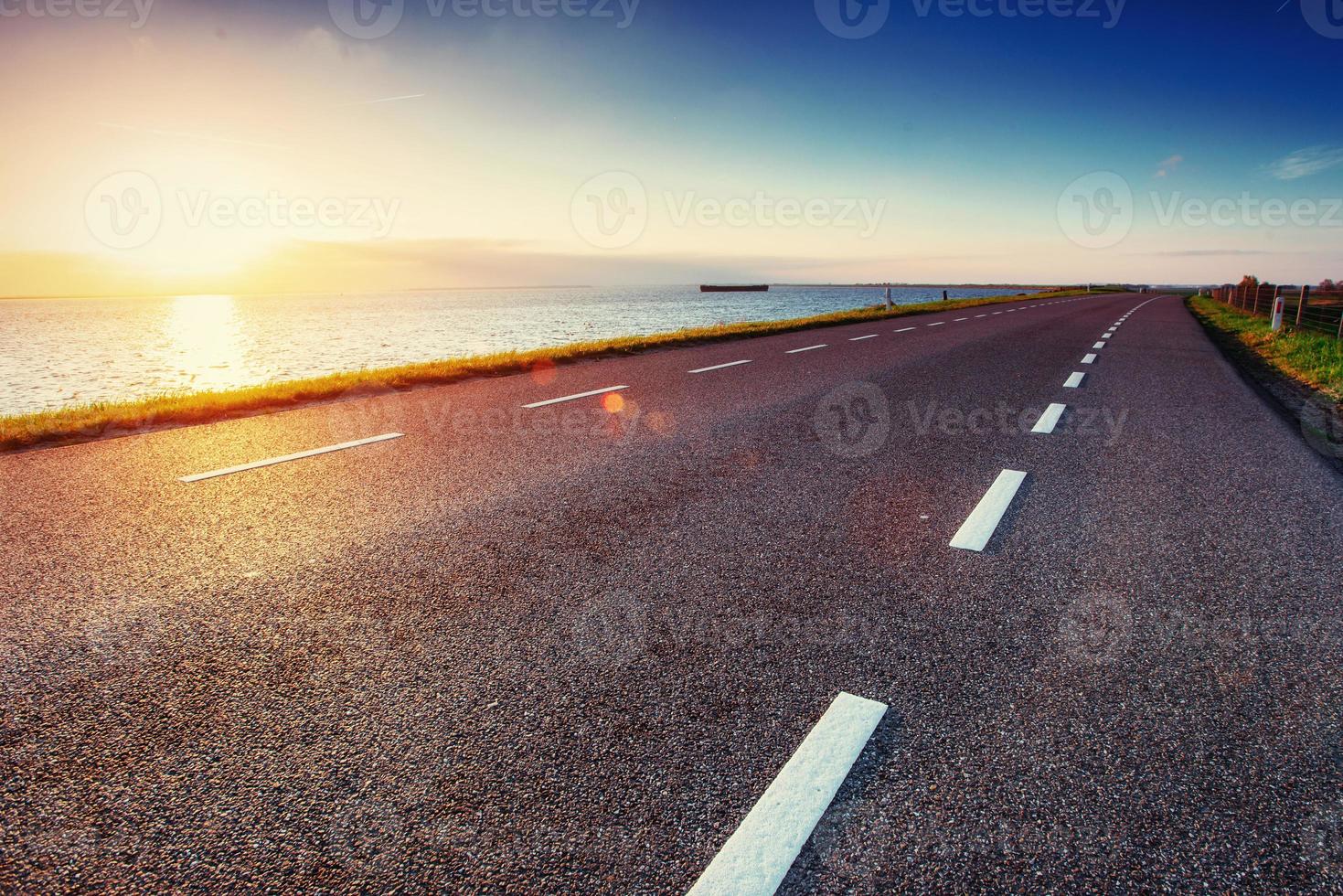 estrada de asfalto ao longo do mar ao pôr do sol foto