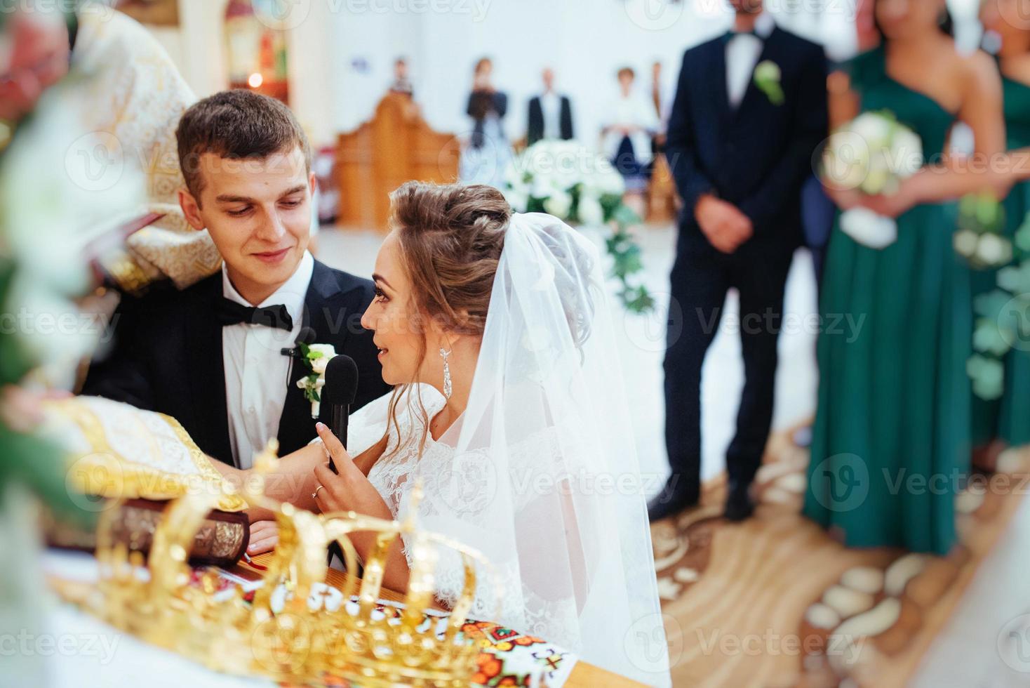 noivo colocando aliança no dedo da noiva durante o casamento foto