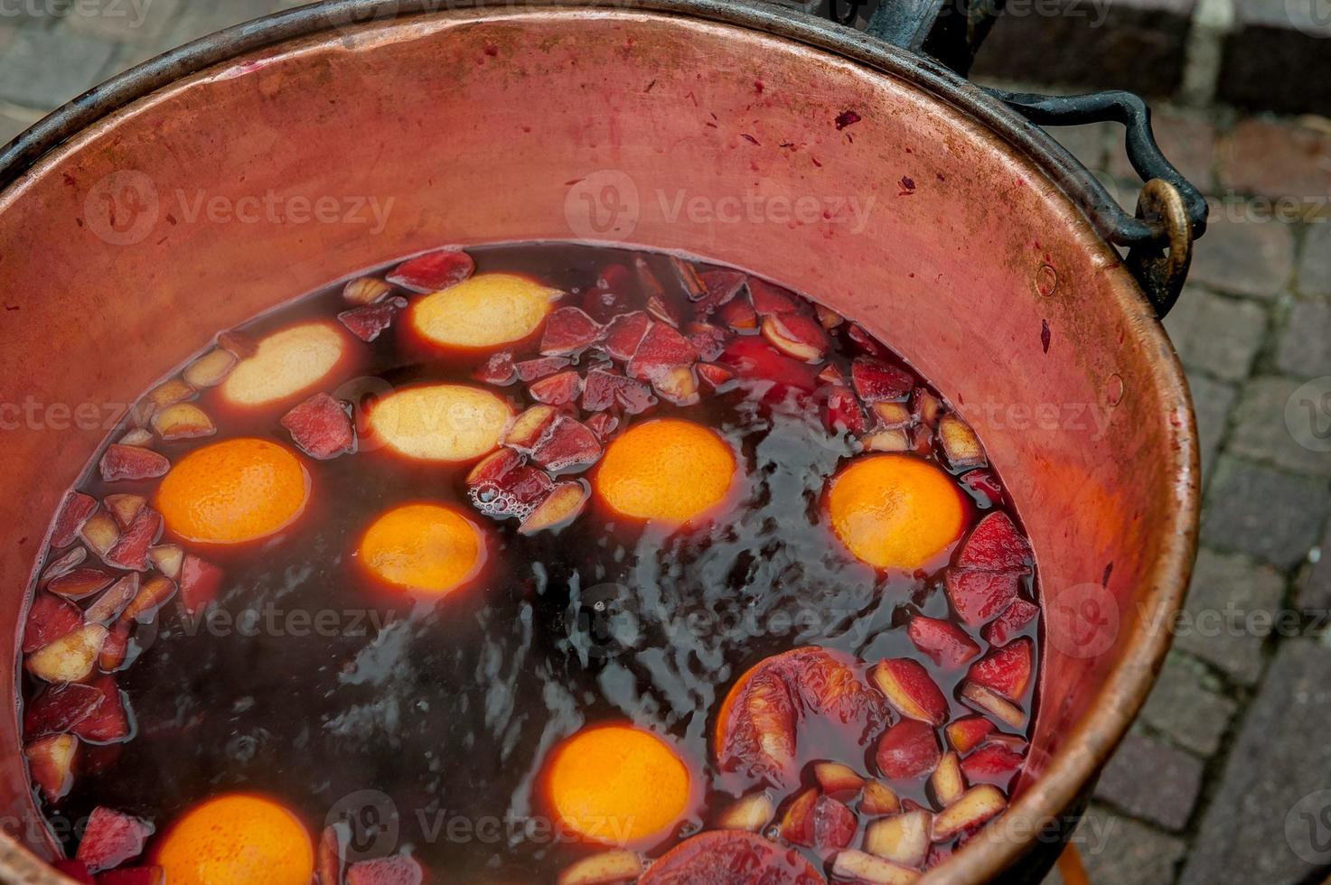 panela de cobre com vinho quente e frutas foto