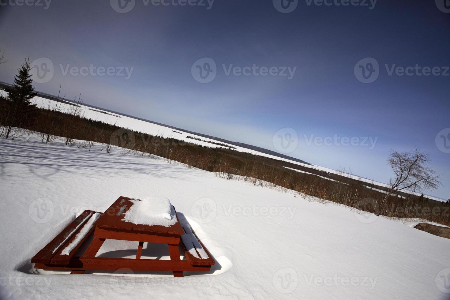 mesa de pinic coberta de neve com vista para o lago dore foto