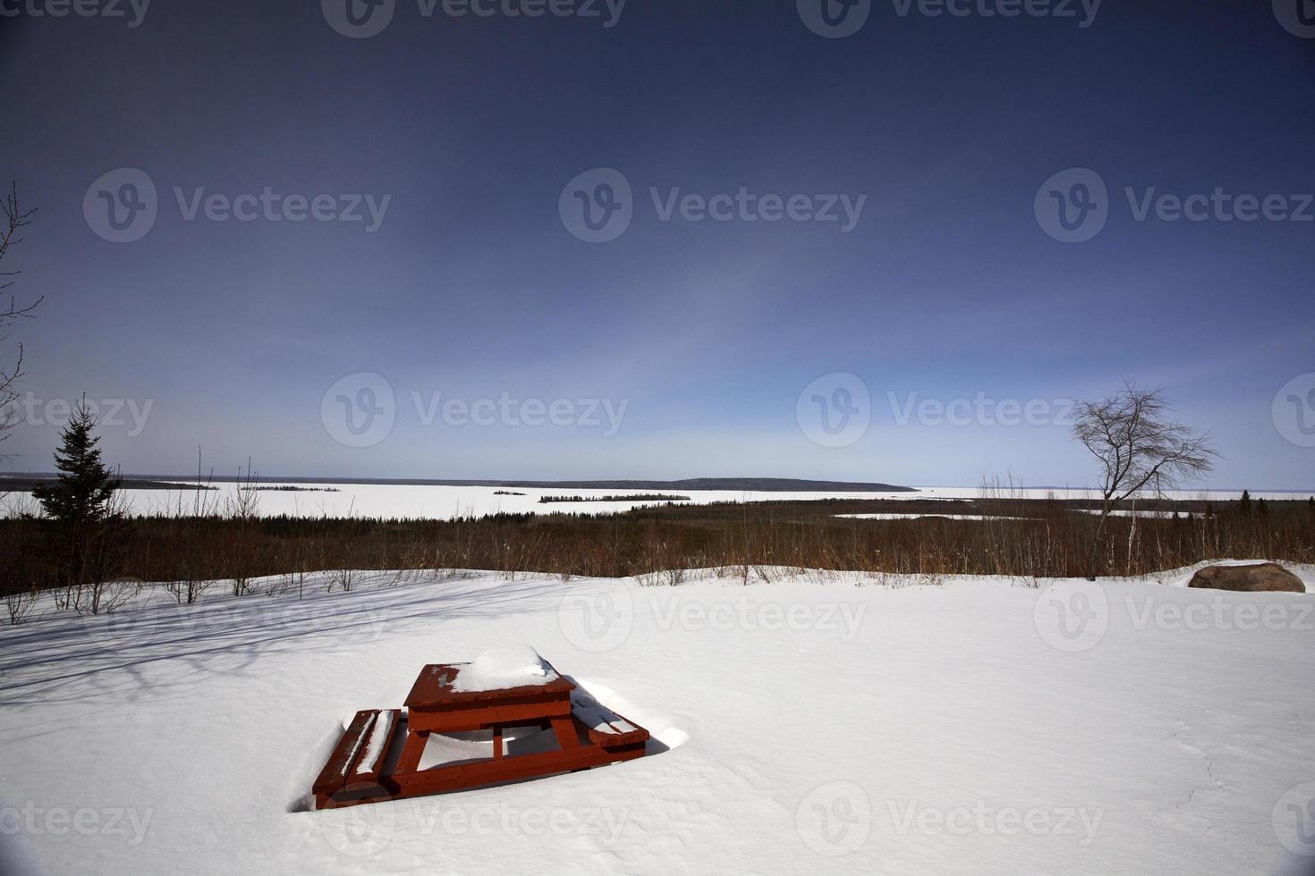mesa de pinic coberta de neve com vista para o lago dore foto