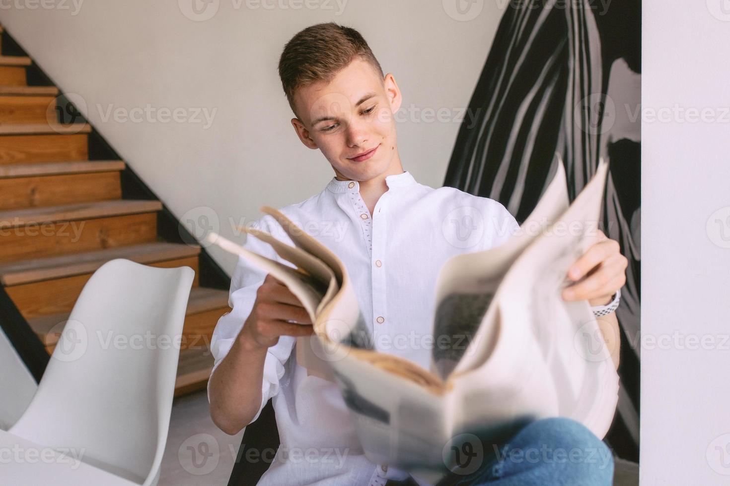 homem adolescente moderno lendo jornal de papel durante o café da manhã em casa. leitura, moda antiga, moderna, conceito de notícias foto