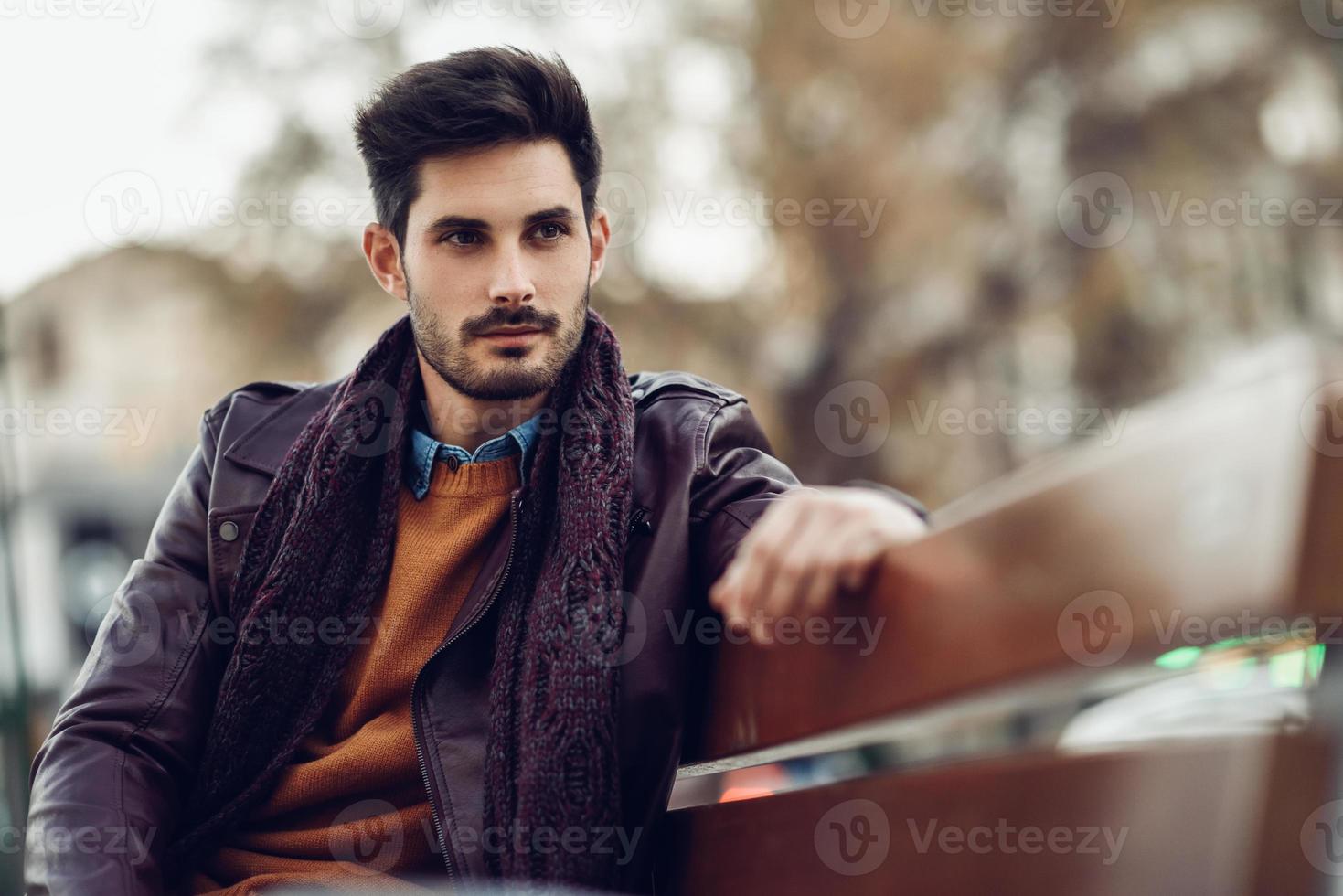 pensativo jovem sentado em um banco urbano. foto