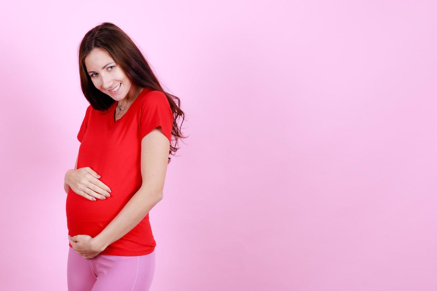 retrato de metade do comprimento da bela jovem modelo grávida caucasiana acariciando concurso toque sua barriga. grávida feliz nova mãe posando interior colocar a mão suave tocando na barriga. conceito de amor e família foto