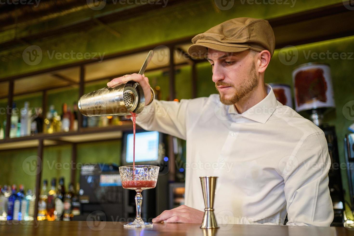 barman derramando coquetel em vidro foto