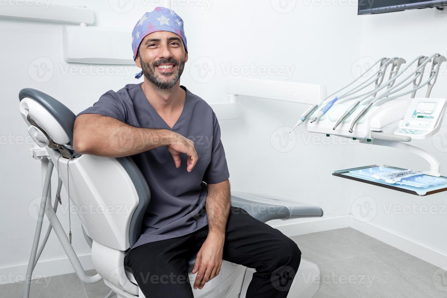 dentista apoiando-se em uma maca em uma clínica odontológica foto