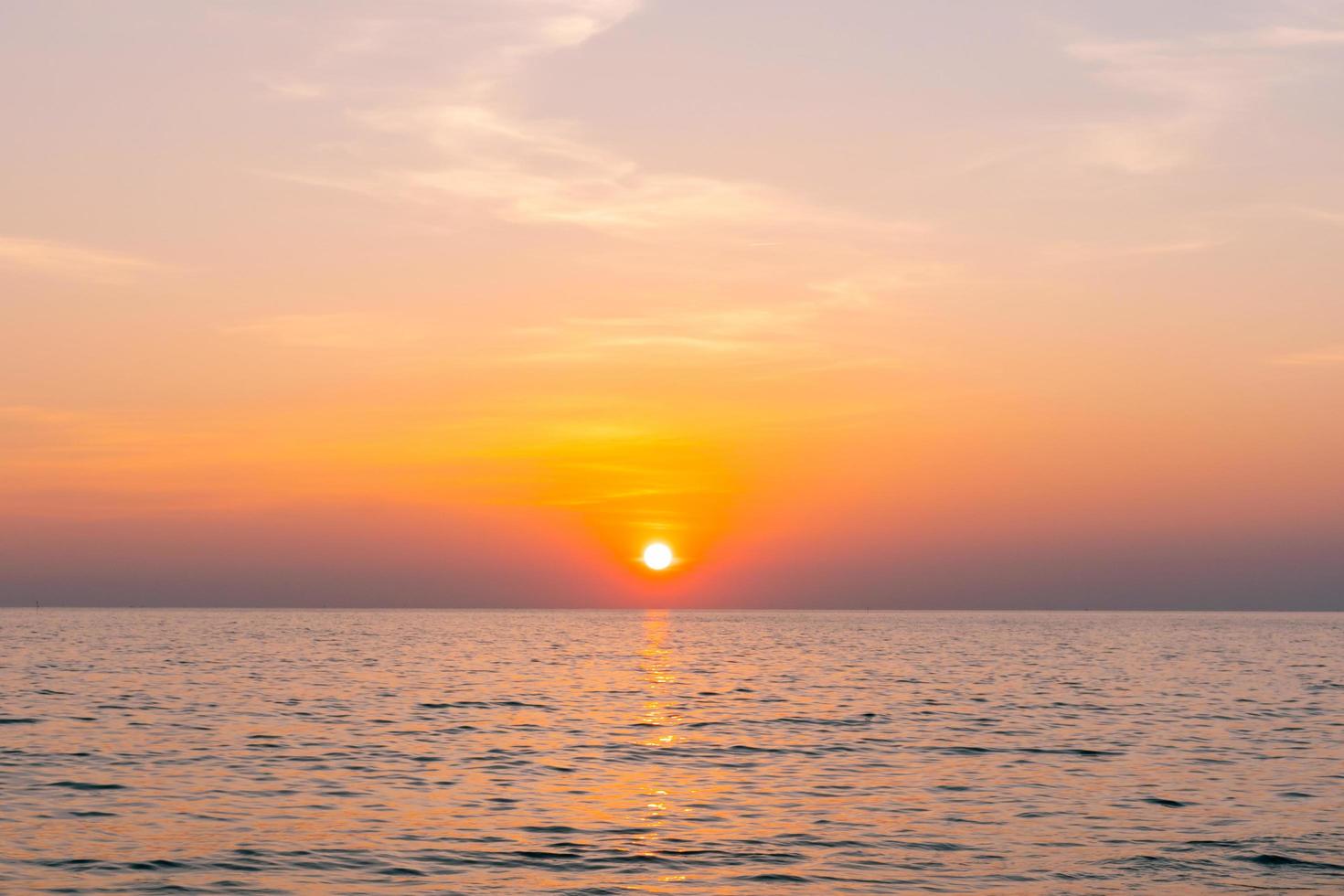 mar de reflexão do sol. belo pôr do sol atrás das nuvens e céu azul acima do fundo da paisagem sobre o mar foto