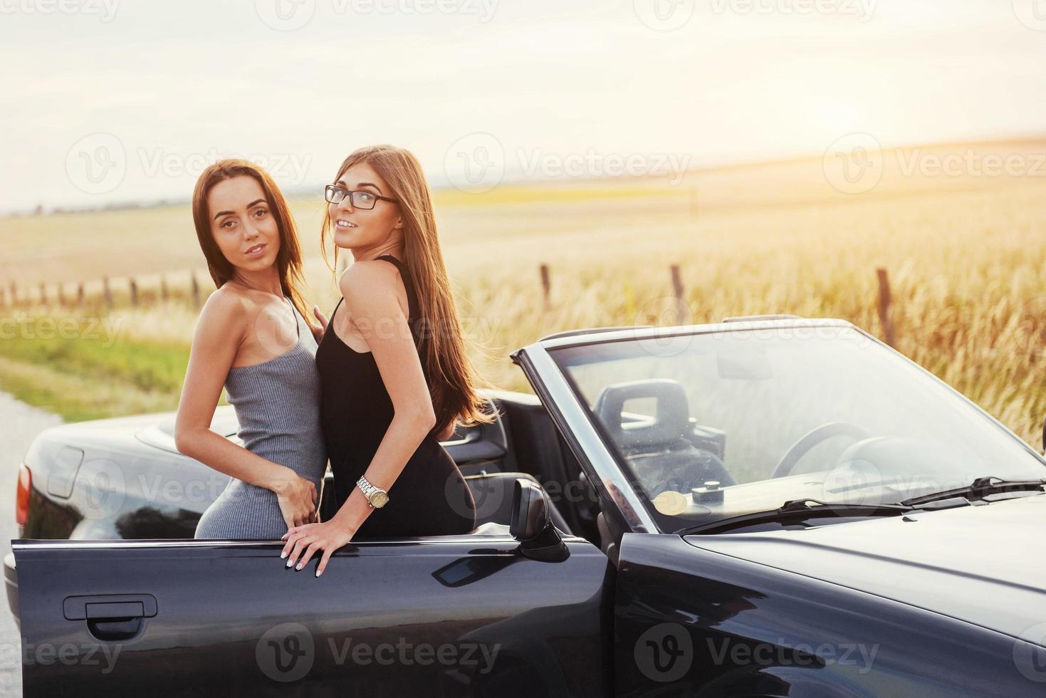 meninas posando para a câmera em um conversível preto foto