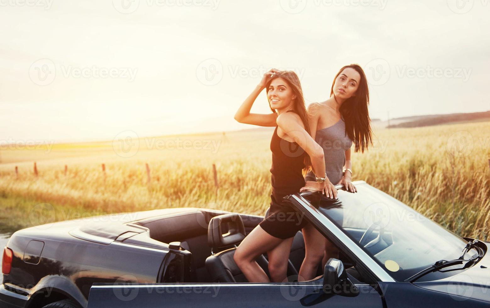 duas mulheres em um carro preto nas estradas à beira da estrada foto