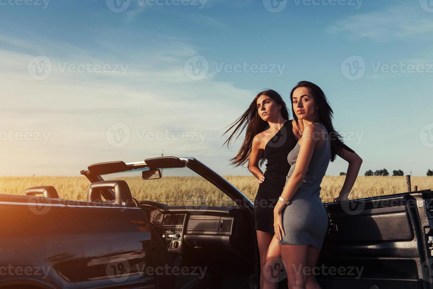 duas mulher morena sexy em pé perto de seu carro foto