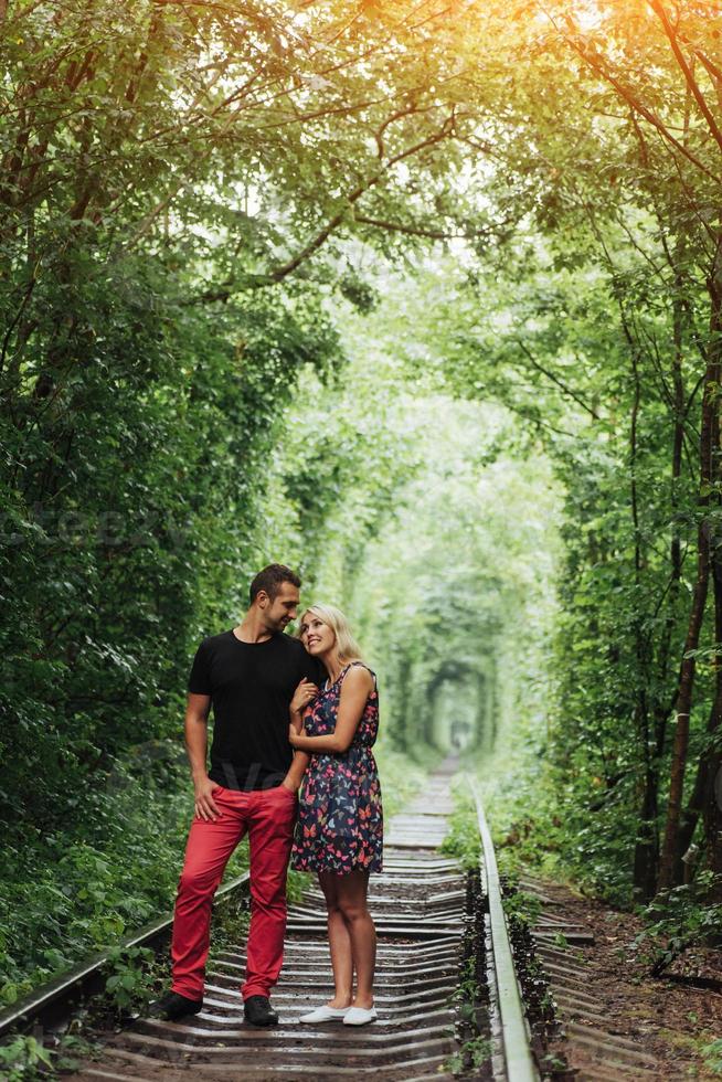 casal apaixonado em um túnel de árvores verdes na ferrovia foto