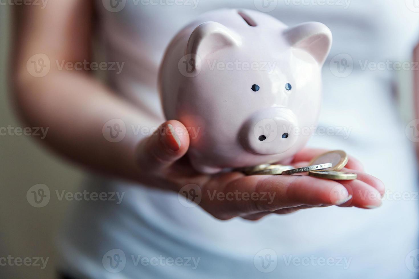 mãos de mulher feminina segurando o cofrinho rosa e moedas de euro. poupança investimento orçamento negócio riqueza aposentadoria financeiro dinheiro bancário conceito. foto