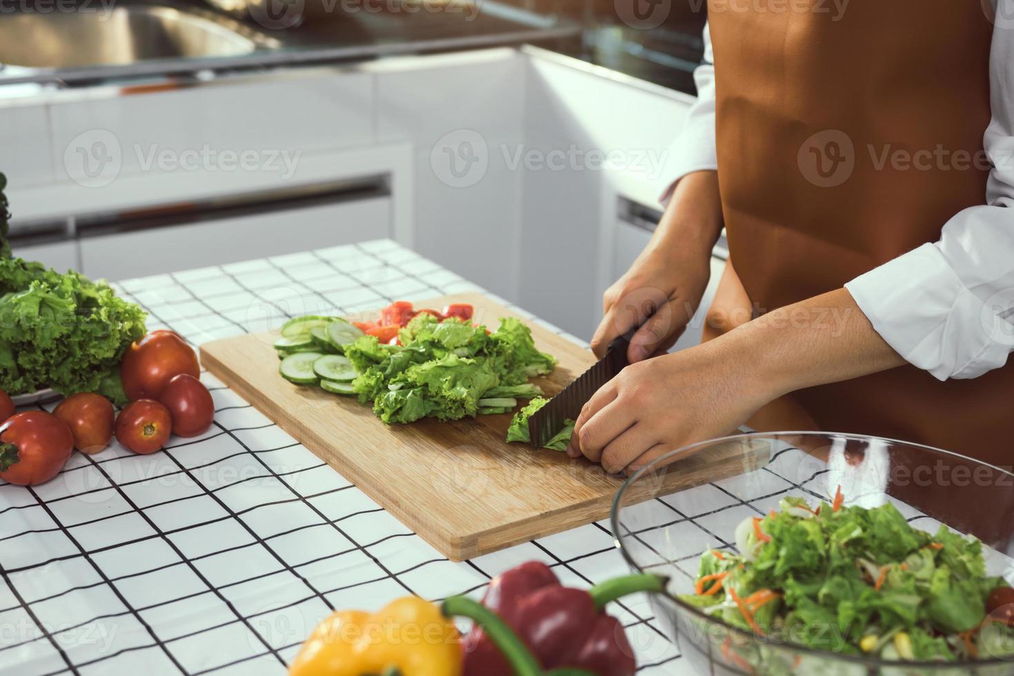 mulher asiática usa uma faca para cortar as verduras na cozinha. foto