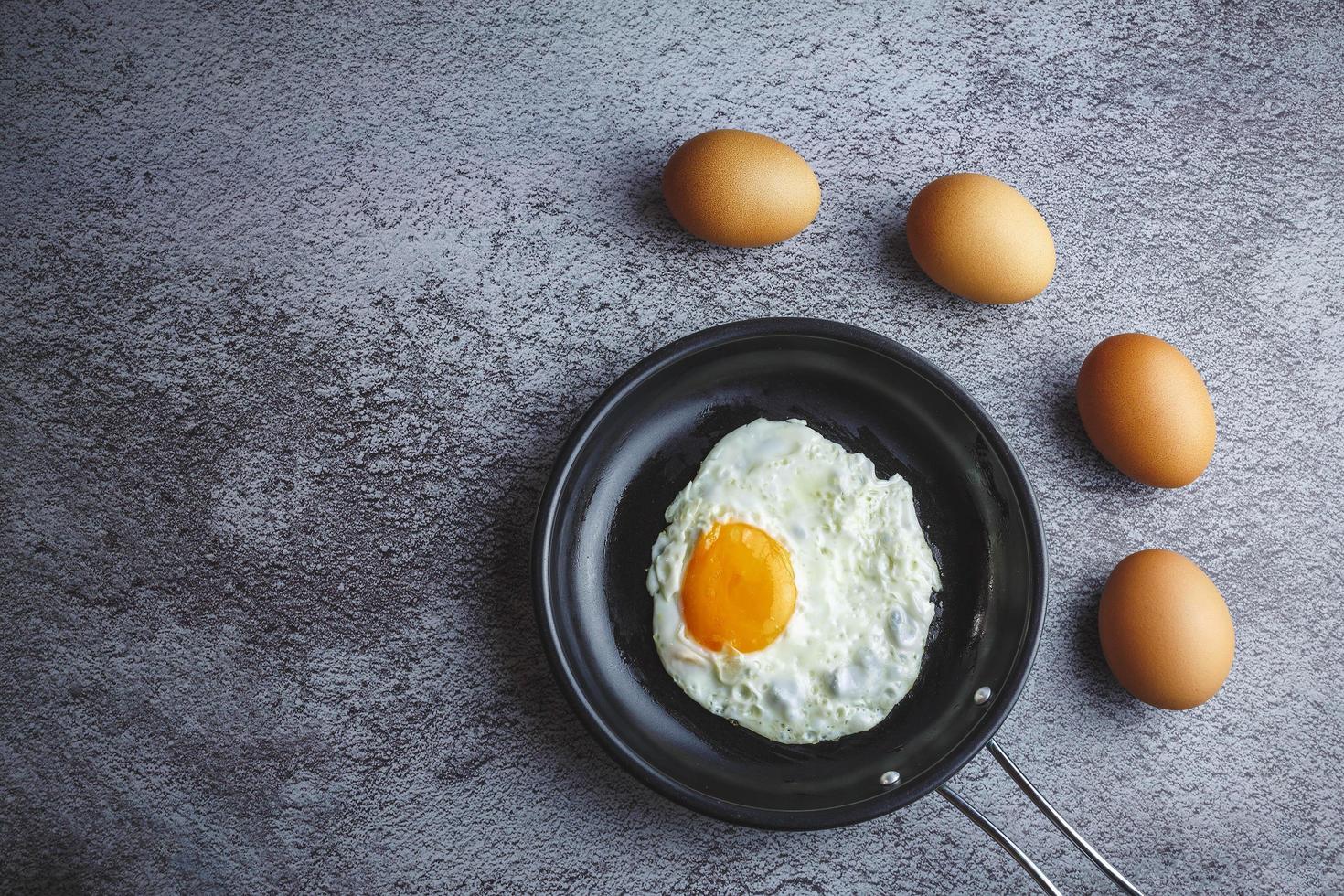 ovos fritos em uma panela e ovos frescos em cima da mesa foto