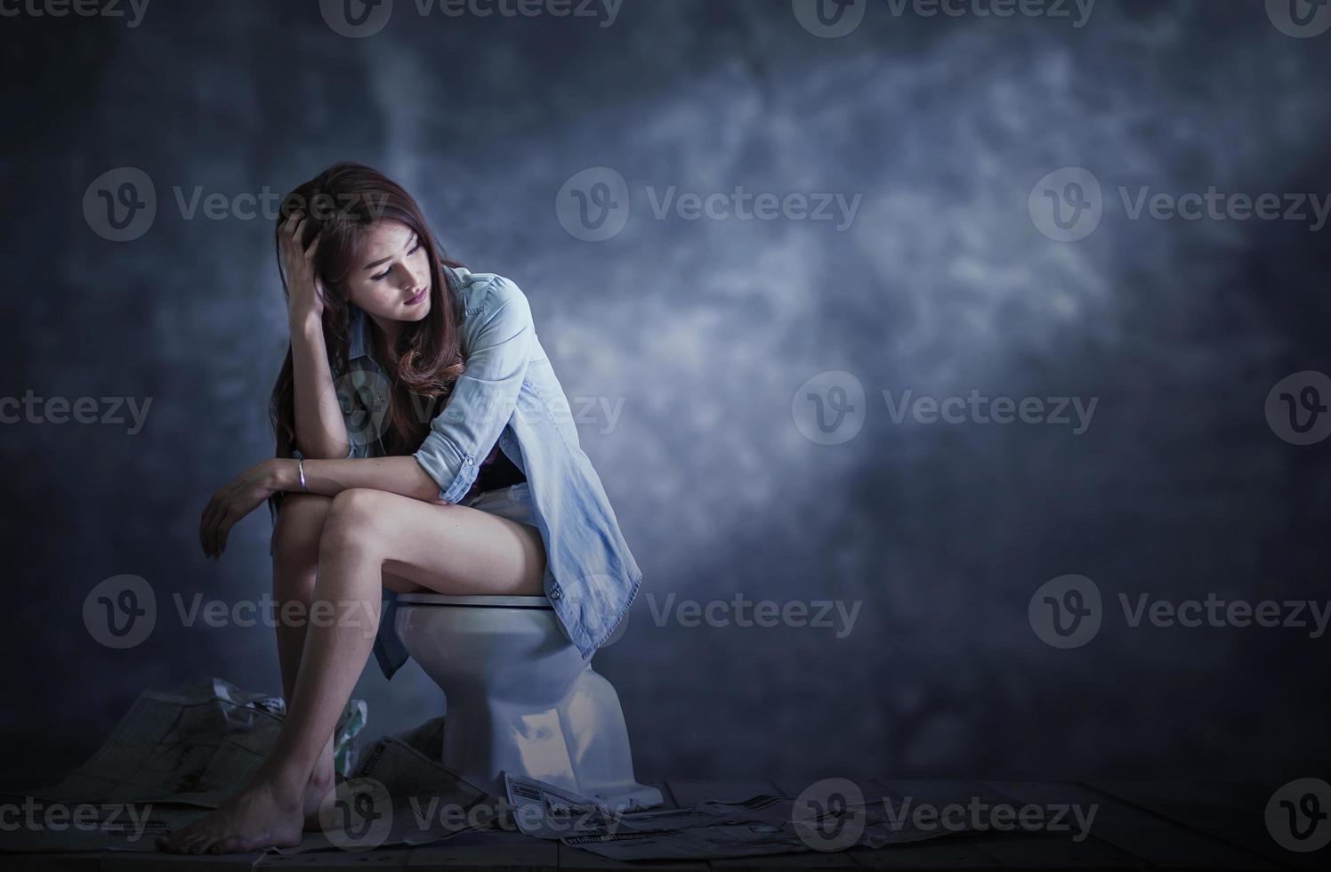 uma mulher se senta em um canto escuro contemplando e preocupada. conceito de depressão foto