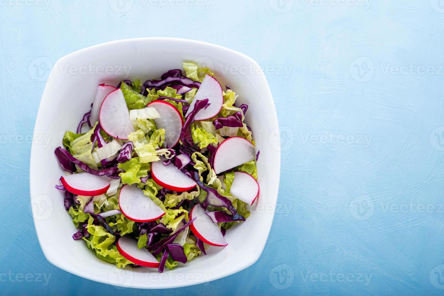 closeup vista de uma tigela de salada verde sobre o pano de fundo azul foto
