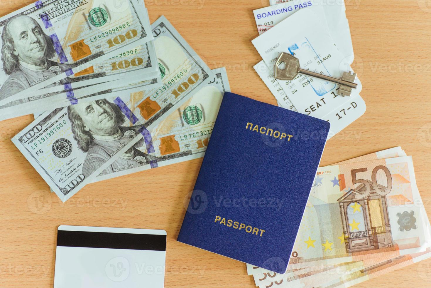passaporte, dólares, chave e cartão bancário em um fundo de madeira. foto
