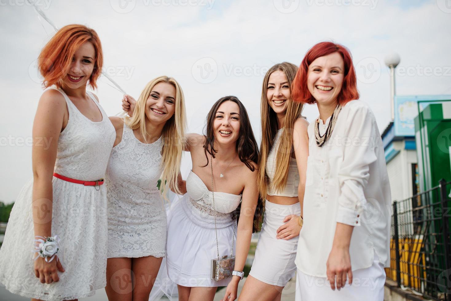 cinco meninas com balões na mão usavam vestidos brancos na festa de despedida contra o cais no lago. foto