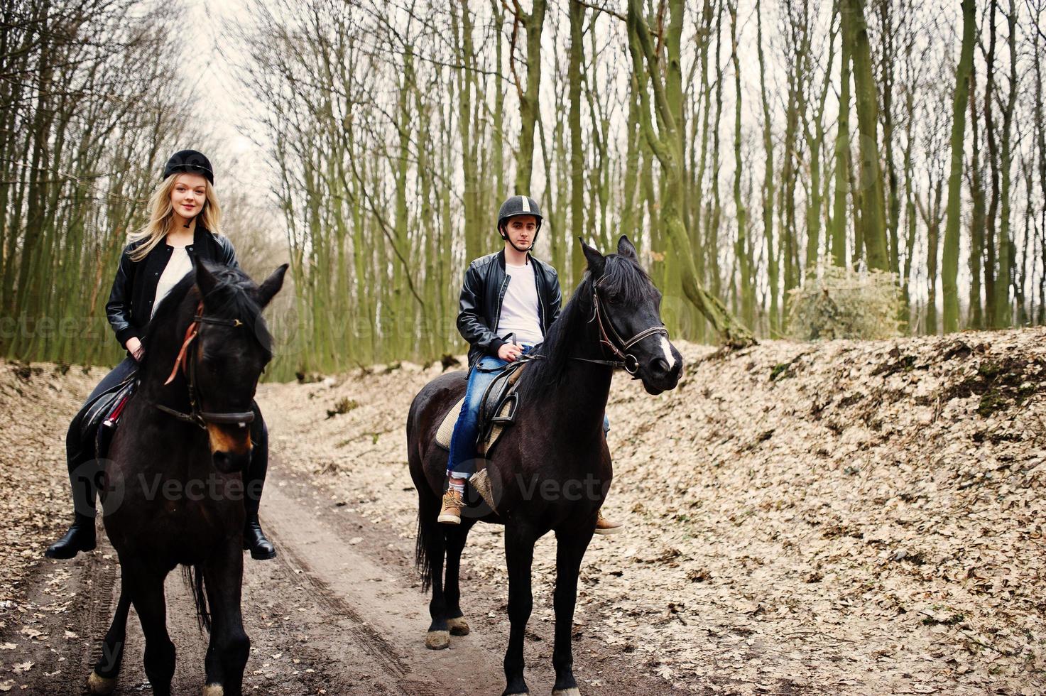 jovem casal elegante montando cavalos na floresta de outono. foto