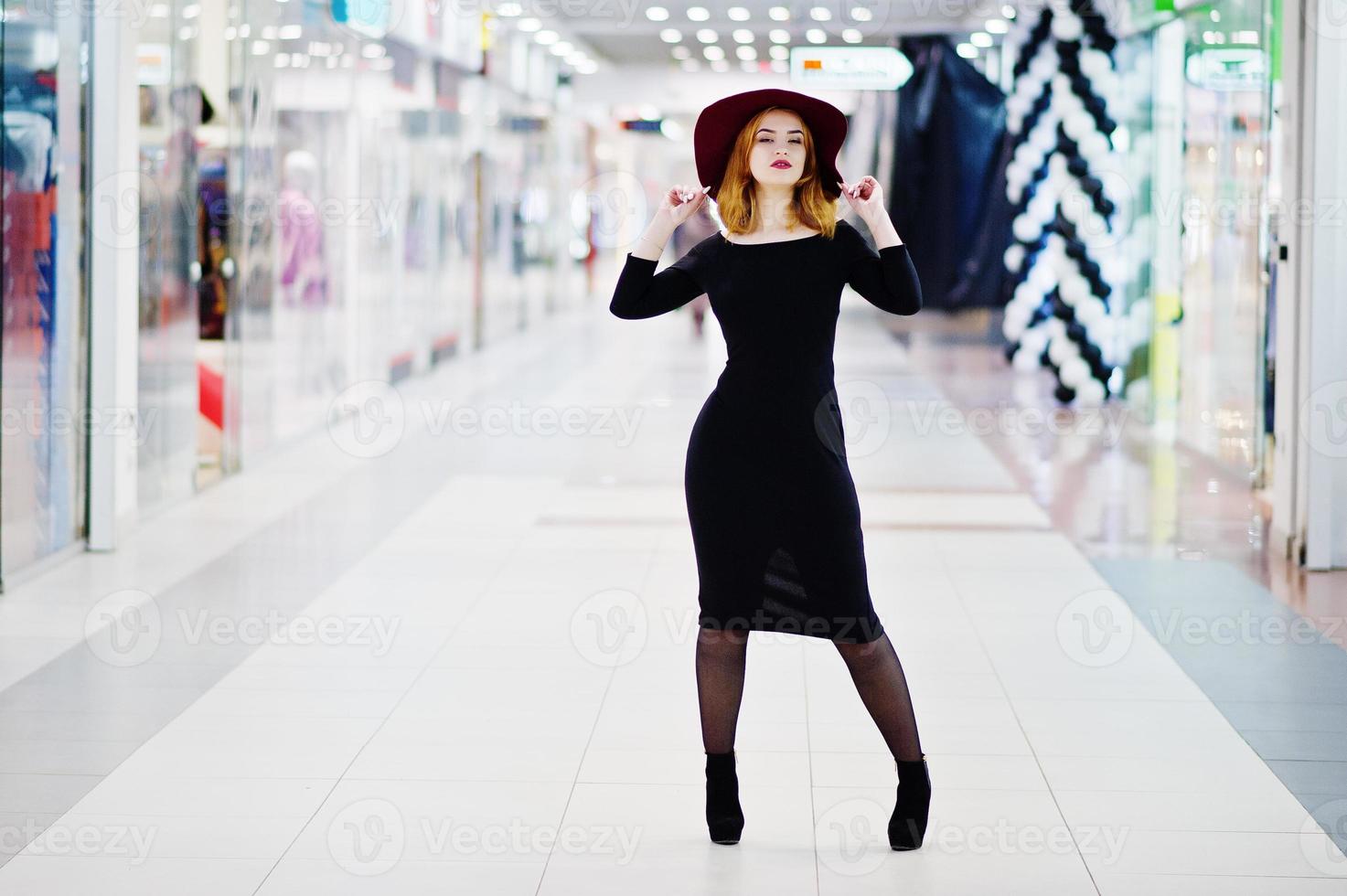 moda garota ruiva usar vestido preto e chapéu vermelho posou no centro comercial de comércio. filtros de instagram de estilo de foto em tons.