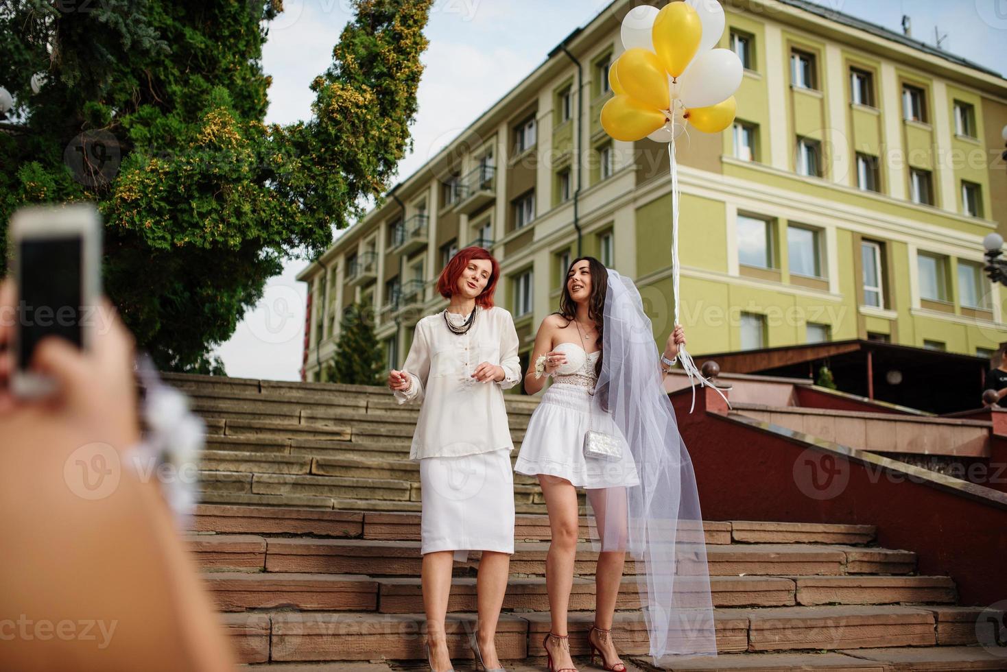 duas garotas com balões à mão na festa de despedida. fazendo foto por telefone.