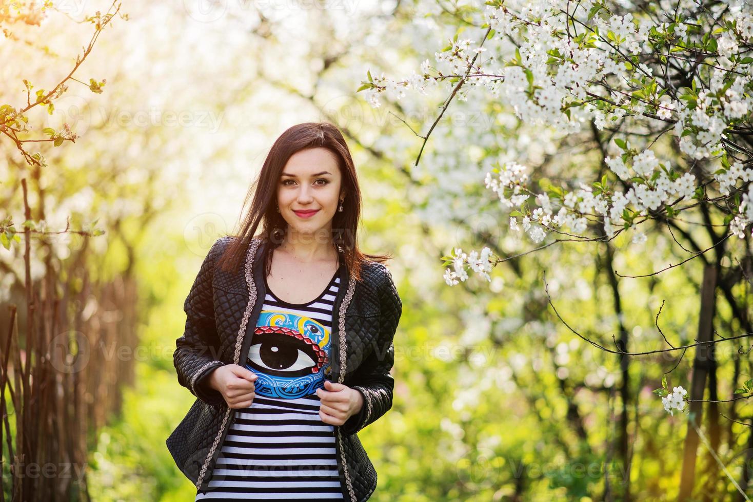 menina morena na jaqueta de couro posou no jardim primavera. foto