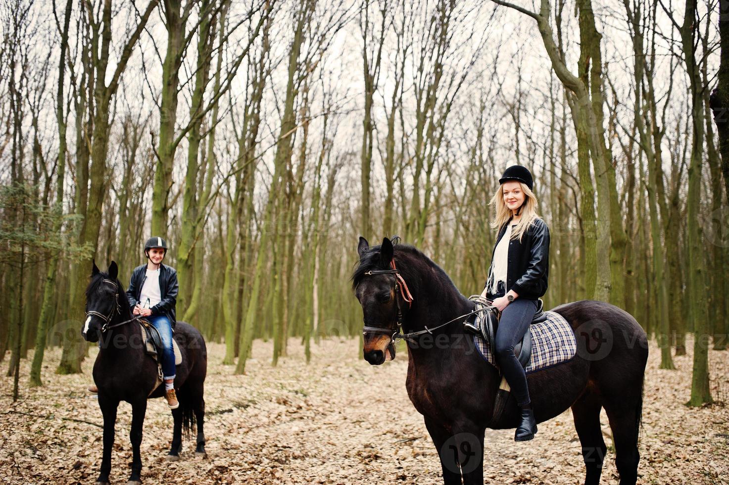 jovem casal elegante montando cavalos na floresta de outono. foto