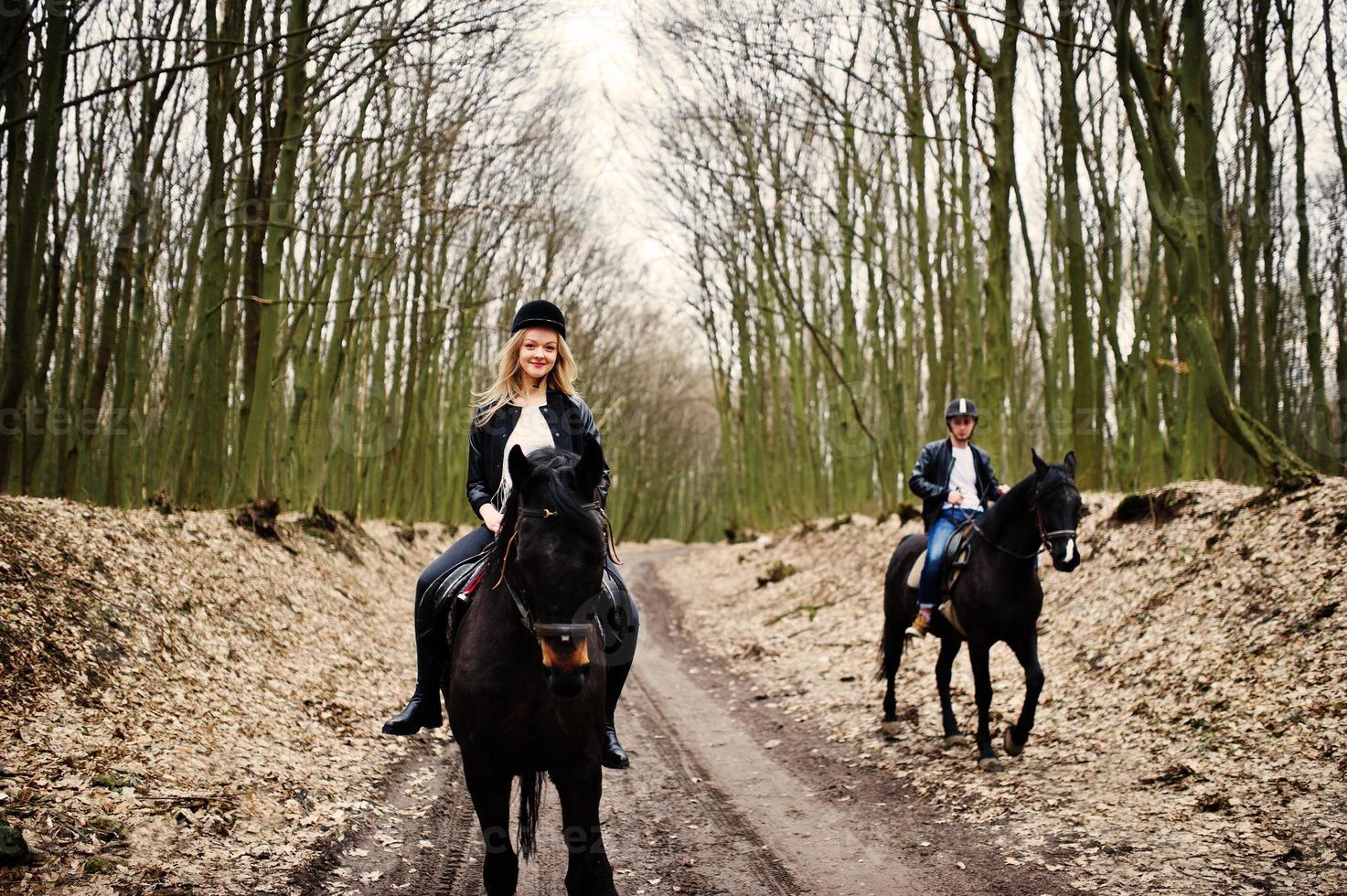 jovem casal elegante montando cavalos na floresta de outono. foto