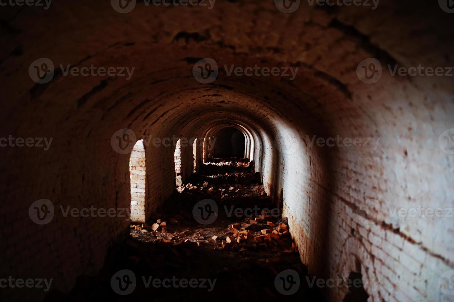 túnel de arco de tijolo assustador no escuro e um pouco de luz. foto