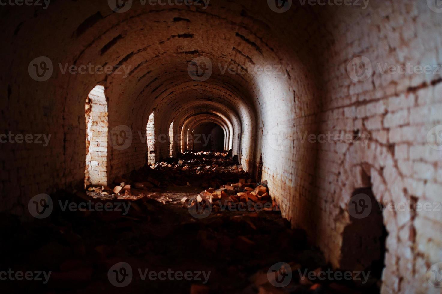 túnel de arco de tijolo assustador no escuro e um pouco de luz. foto