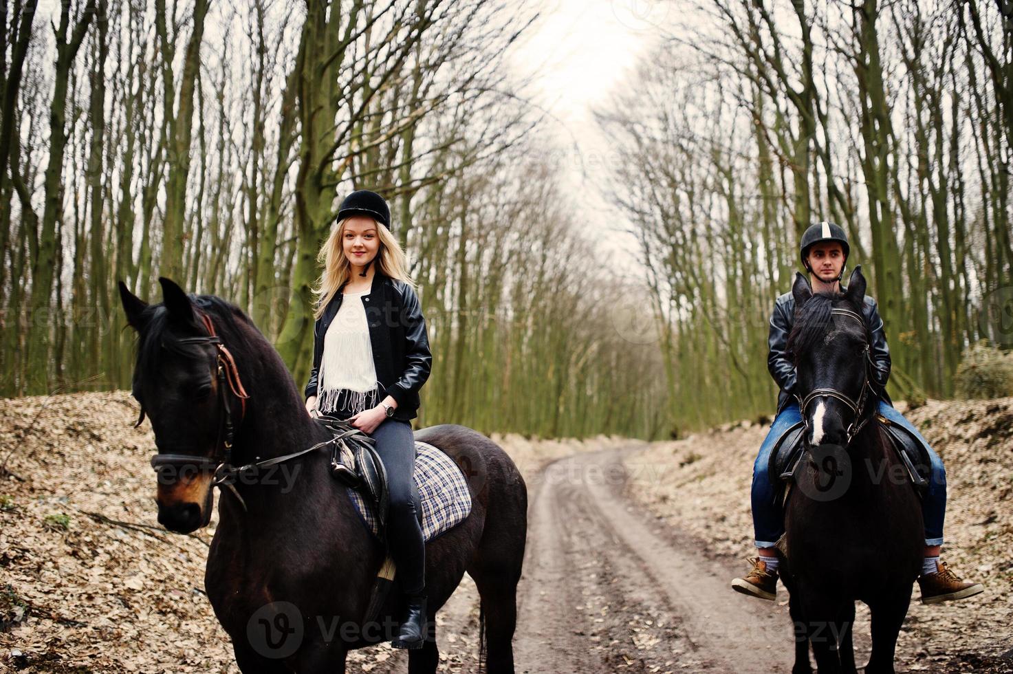 jovem casal elegante montando cavalos na floresta de outono. foto