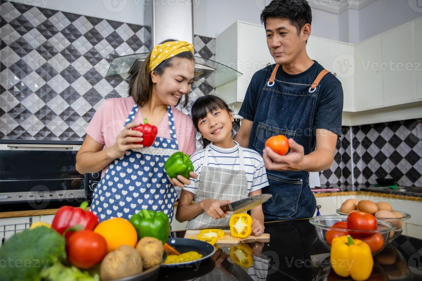 família feliz tem pai, mãe e sua filha cozinhando juntos na cozinha foto