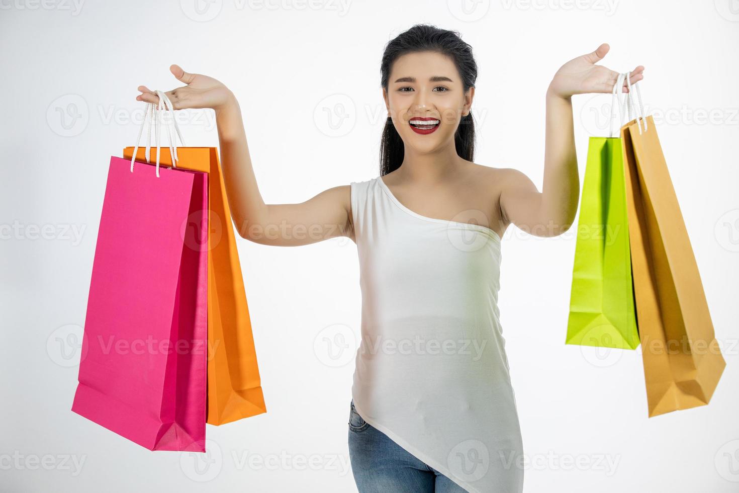 Linda garota asiática segurando sacolas de compras e sorrindo foto