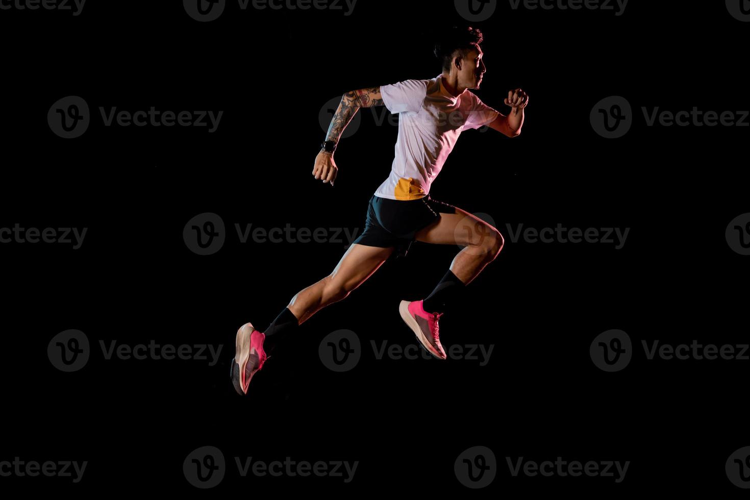 jovem corredor velocista asiático correndo no estúdio em fundo preto foto