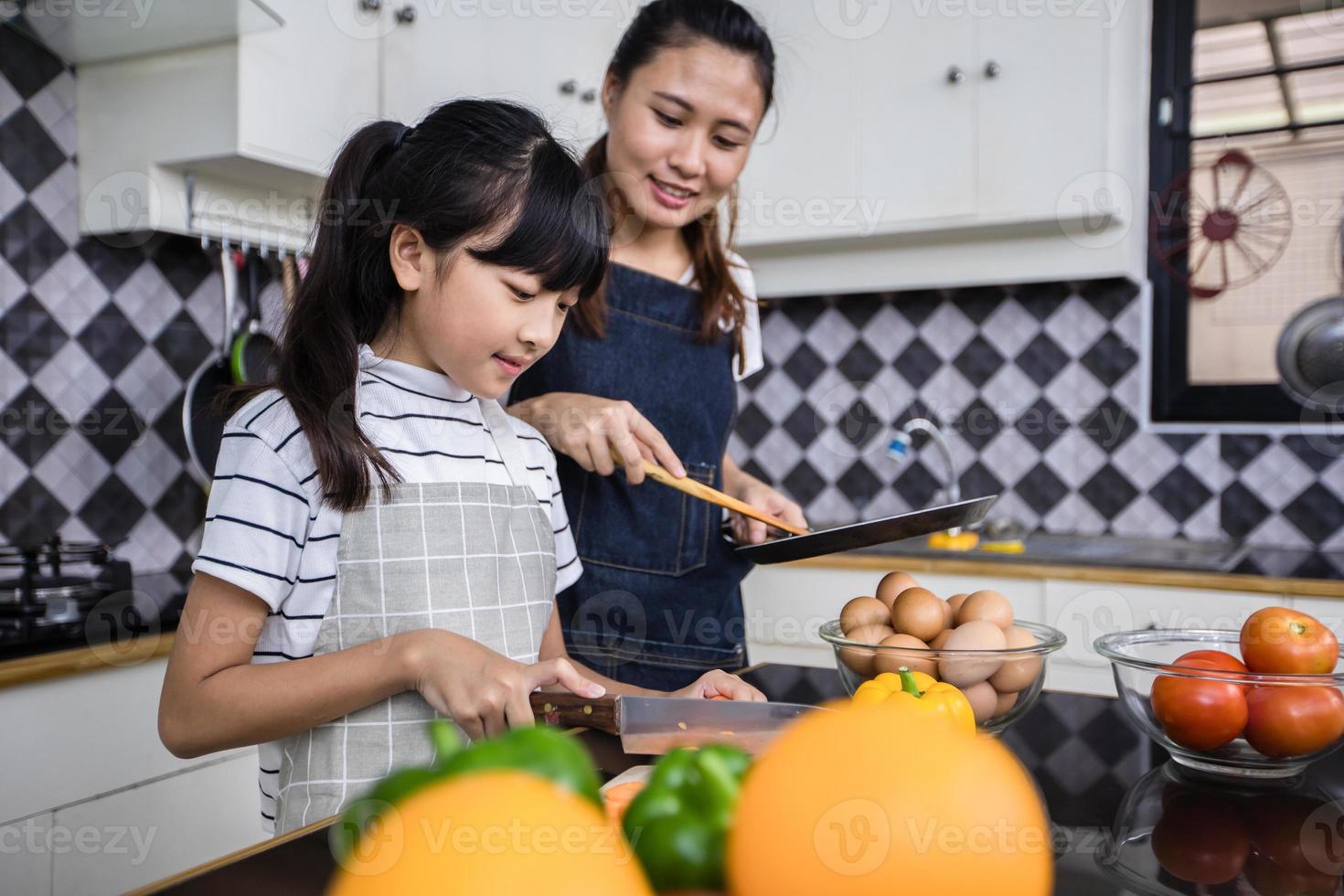 famílias asiáticas estão cozinhando e os pais estão ensinando suas filhas a cozinhar na cozinha de casa. atividades familiares nos feriados e felizes no conceito de recreação foto