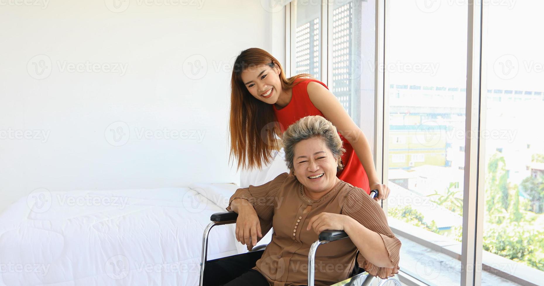 mulher alegre cuidando de sua avó em cadeira de rodas foto