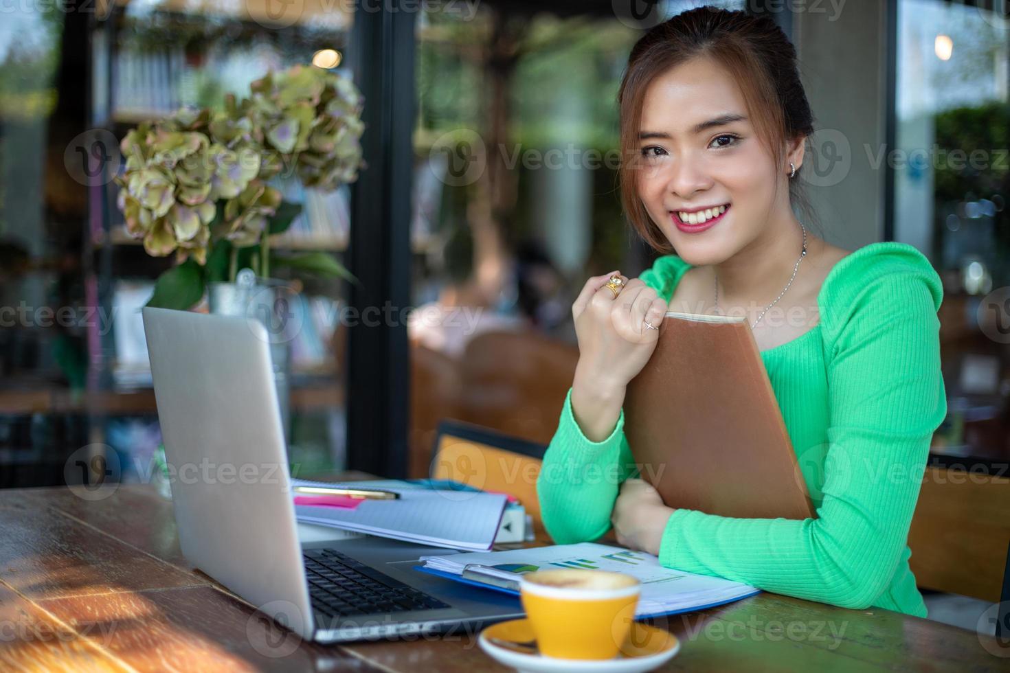 mulheres asiáticas lendo livro e sorrindo e feliz relaxando em um café depois de trabalhar em um escritório de sucesso. foto