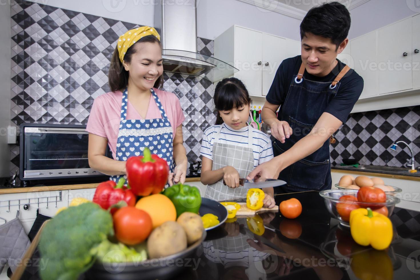 famílias asiáticas estão cozinhando e os pais estão ensinando suas filhas a cozinhar na cozinha de casa. atividades familiares nos feriados e felizes no conceito de recreação foto