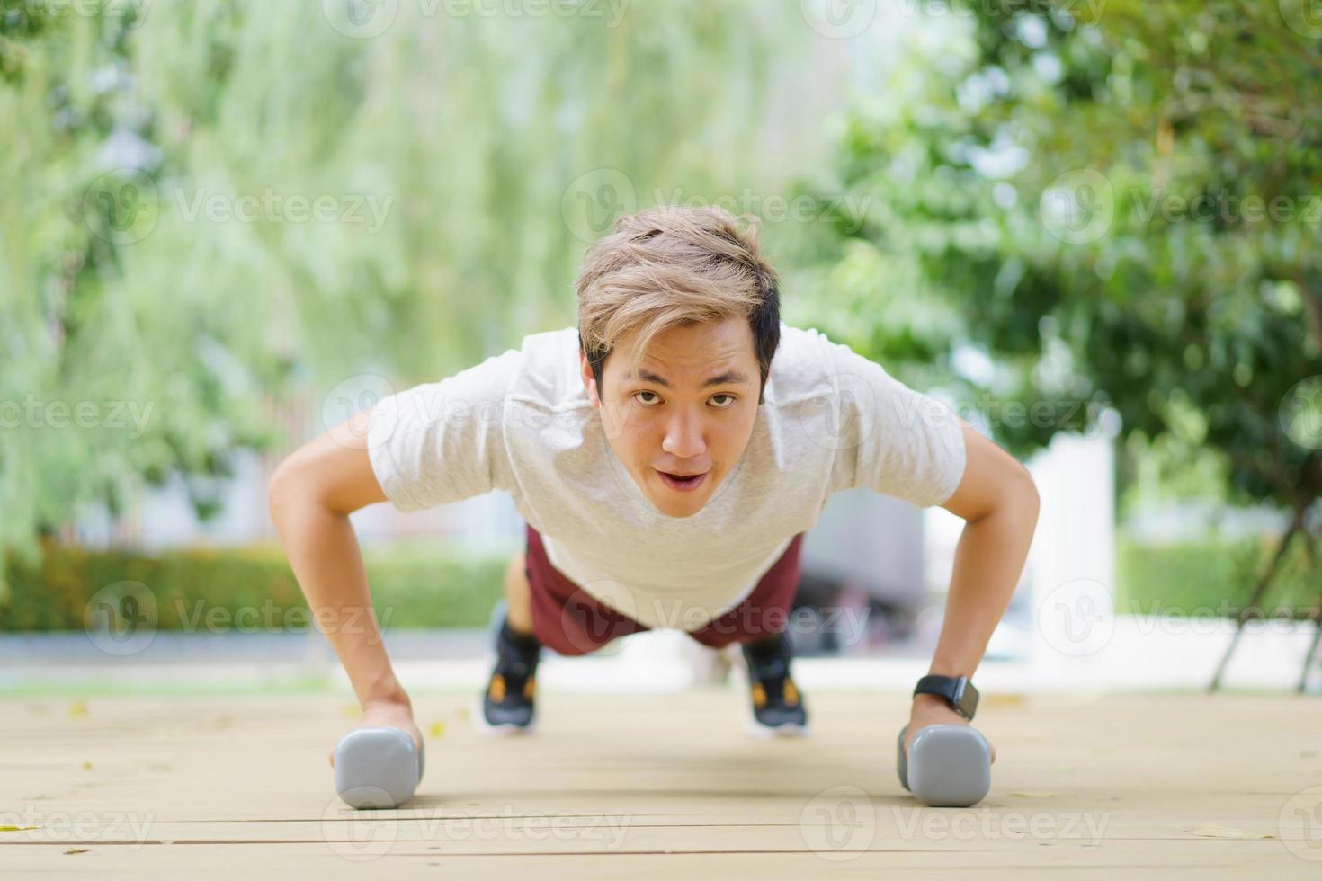 esportista asiático fazendo um exercício de peso corporal usando halteres. foto