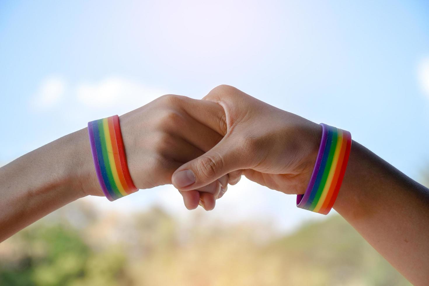 pulseiras de borracha arco-íris nos pulsos de casal asiático com fundo desfocado, conceito para celebração da comunidade lgbt no mês do orgulho ou em junho em todo o mundo. foto